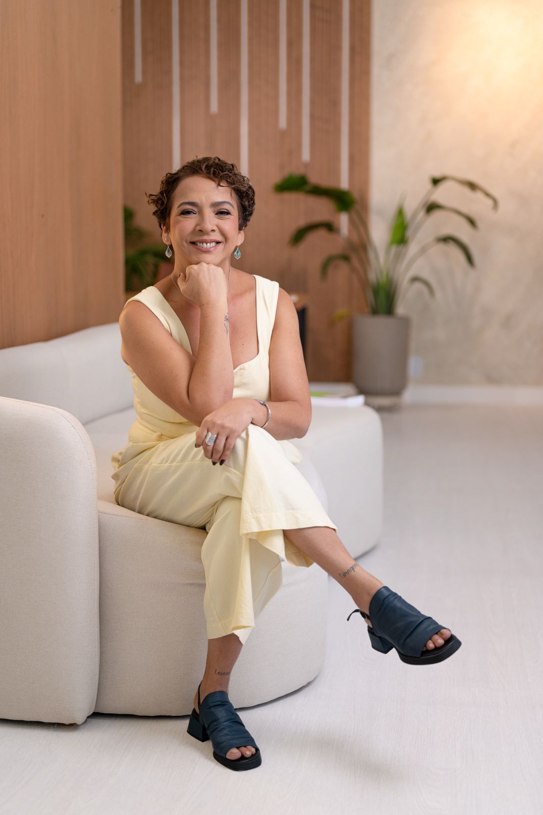 Patrícia Sena em seu consultório em Itaquera, sentada no sofá com postura acolhedora